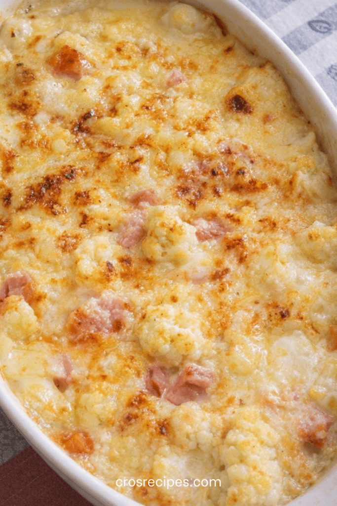 Gratin de chou-fleur au jambon maigre et mozzarella légère doré au four, servi dans un plat gratiné avec sauce crémeuse légère et herbes fraîches.