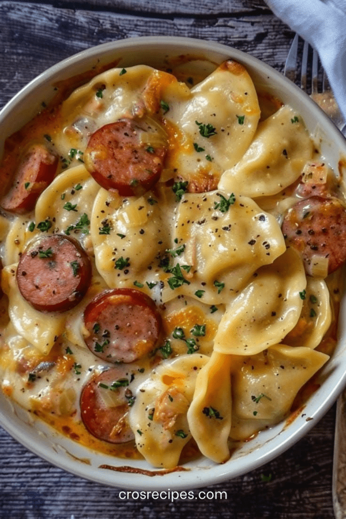 Crockpot Pierogi Casserole avec kielbasa fumée, pierogi fondants, sauce crémeuse au cheddar, oignons dorés et persil frais dans une mijoteuse