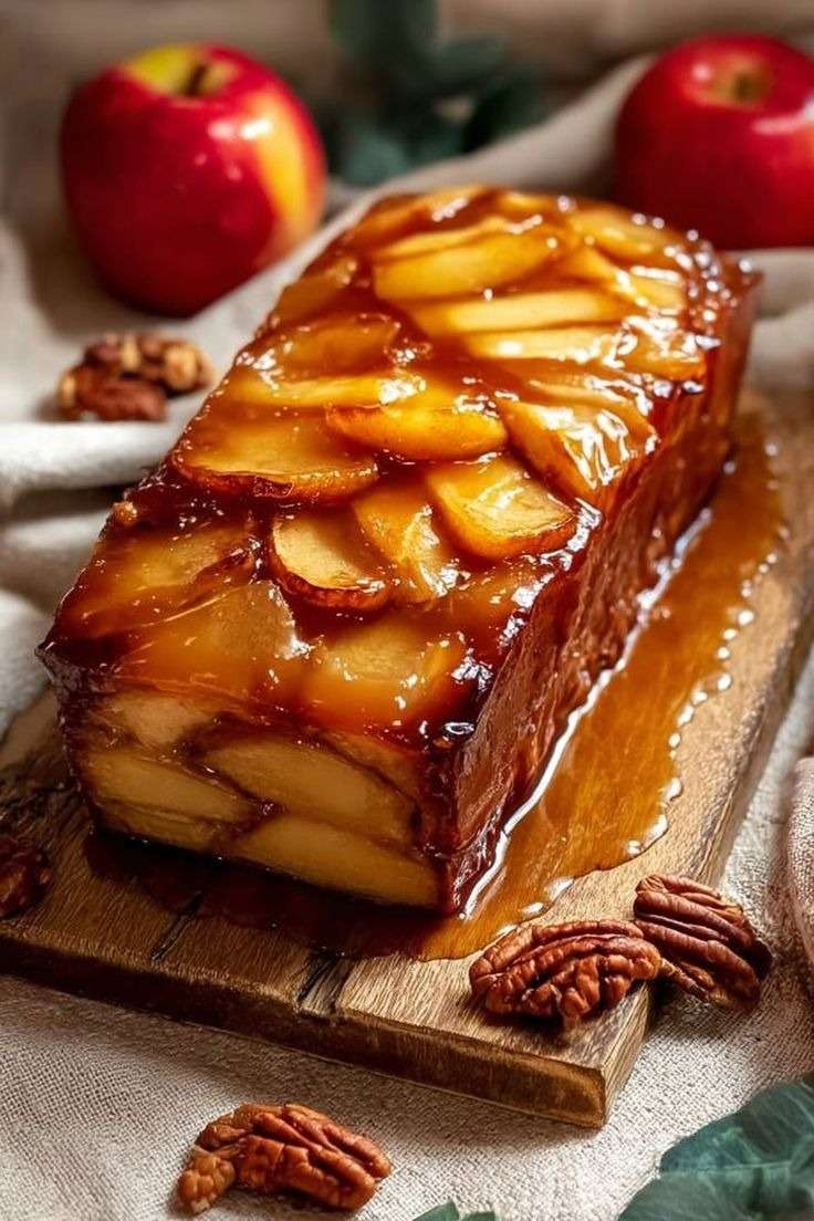 Tranches de terrine aux pommes caramélisées, dorées et fondantes, servies sur assiette avec nappage caramel et quelques noix de pécan.