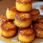 Petites bouchées de pain de maïs dorées, moelleuses à l’intérieur, brillamment glacées au miel et servies chaudes sur une assiette.