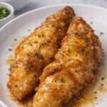 Aiguillettes de poulet panées et dorées, nappées d’une sauce au miel brillante légèrement caramélisée, servies chaudes avec persil frais.