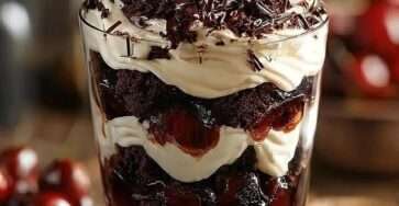 Verrine forêt-noire avec couches de gâteau au chocolat, chantilly maison, cerises juteuses et copeaux de chocolat noir.