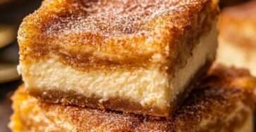 Carrés cheesecake churros dorés avec cœur crémeux au fromage frais et finition sucre-cannelle, servis sur une assiette.