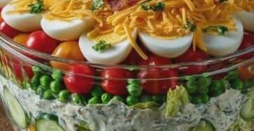 Grande salade sept étages américaine dans un saladier transparent avec couches de laitue, légumes, œufs, cheddar et bacon croustillant.