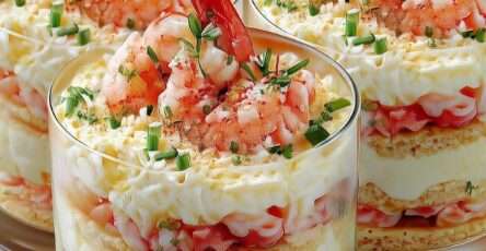 Verrines crémeuses aux crevettes avec fromage frais citronné, crackers croustillants et ciboulette, décorées d’une crevette entière et paprika.