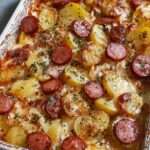 gratin de pommes de terre et saucisse fumée au fromage doré au four avec sauce crémeuse et persil frais dans un plat à gratin rustique