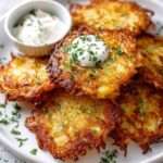 Galettes de pommes de terre dorées et croustillantes servies avec crème fraîche et ciboulette sur une assiette rustique.