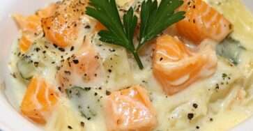 Blanquette de saumon crémeuse avec poireaux et carottes servie dans une assiette avec sauce onctueuse et persil frais.