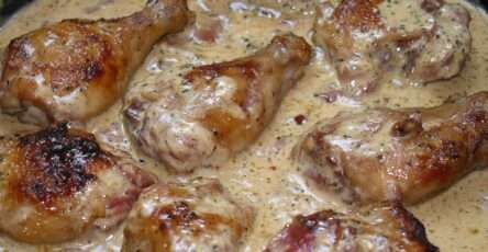 Pilons de poulet dorés nappés d’une sauce crémeuse au Porto avec lardons, persil frais et échalotes dans une poêle rustique.