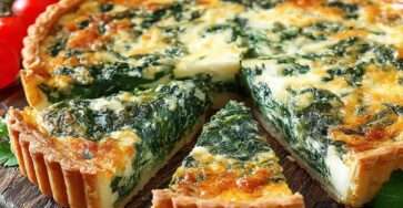 Quiche épinards et fromage dorée au four, avec garniture crémeuse, pâte croustillante et tomates cerises en accompagnement.