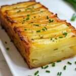 Gâteau invisible salé aux fines lamelles de pommes de terre et comté gratiné, servi en tranches, avec une texture fondante et une finition à la ciboulette fraîche.