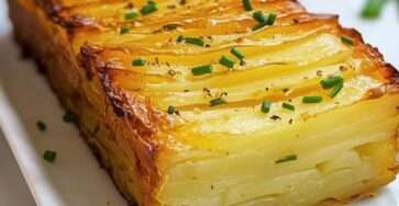 Gâteau invisible salé aux fines lamelles de pommes de terre et comté gratiné, servi en tranches, avec une texture fondante et une finition à la ciboulette fraîche.
