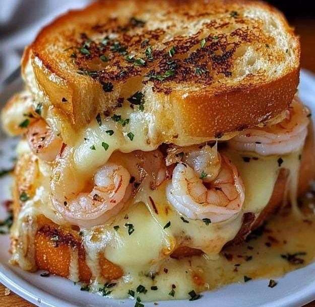 Croque-monsieur aux crevettes avec pain doré croustillant, fromage fondu filant et garniture crémeuse aux crevettes et persil frais.