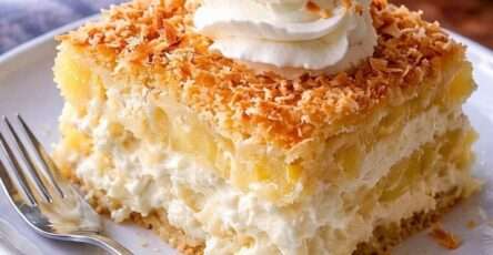 Gâteau ananas coco crémeux avec base moelleuse, crème mascarpone onctueuse, morceaux d’ananas et noix de coco râpée dorée sur le dessus.