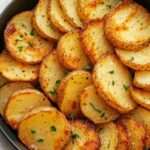 Rondelles de pommes de terre dorées et croustillantes cuites à l’air fryer, assaisonnées au paprika, aux herbes et garnies de persil frais dans une assiette de service.