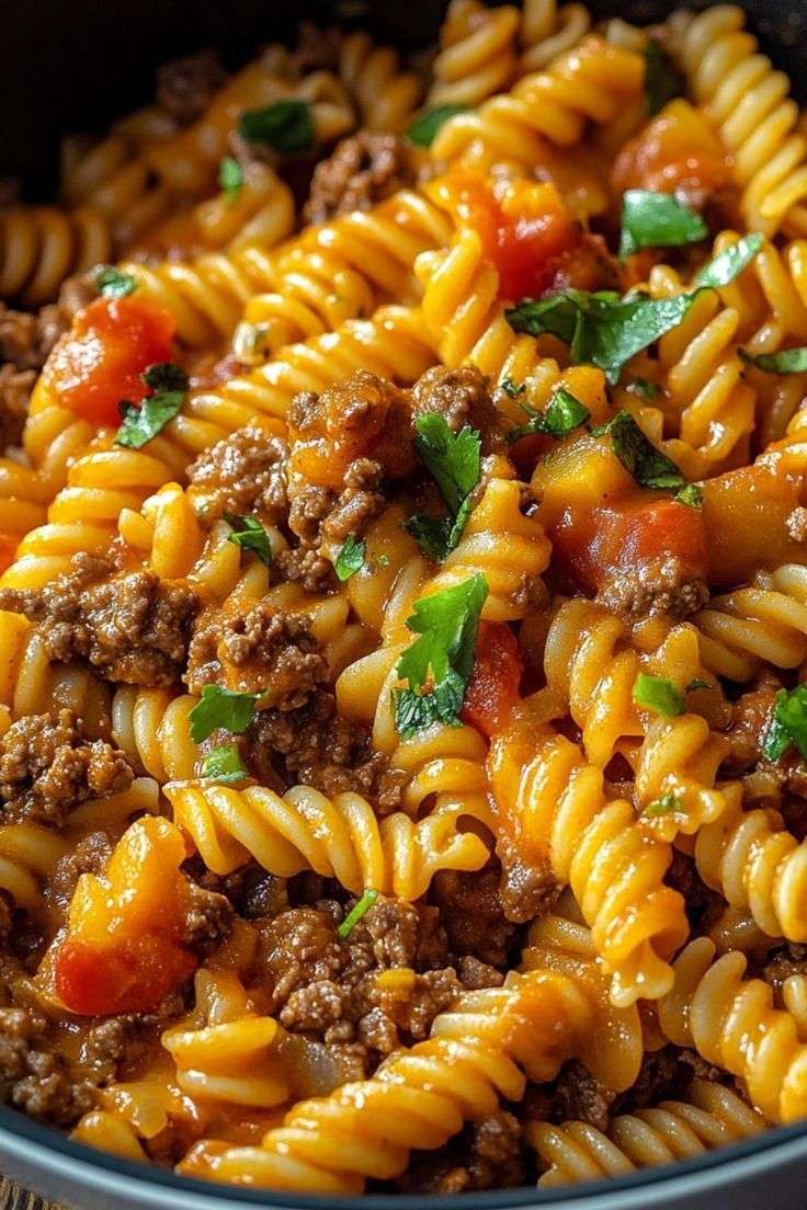 Assiette de fusilli au bœuf haché et à la tomate, nappés d’une sauce rouge brillante, garnis de persil frais haché et servis bien chauds.