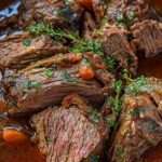 Bœuf braisé à l’italienne servi dans une cocotte, viande fondante nappée de sauce au vin rouge avec carottes, céleri et herbes fraîches.