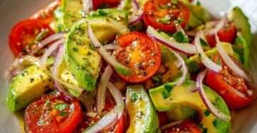 Salade fraîche avec avocat en cubes, tomates cerises coupées et fines lamelles d’oignon rouge, assaisonnée d’huile d’olive et citron.
