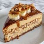 Cheesecake sans cuisson à la banane, nappé de caramel coulant et parsemé de cacahuètes croquantes sur une base biscuitée dorée.