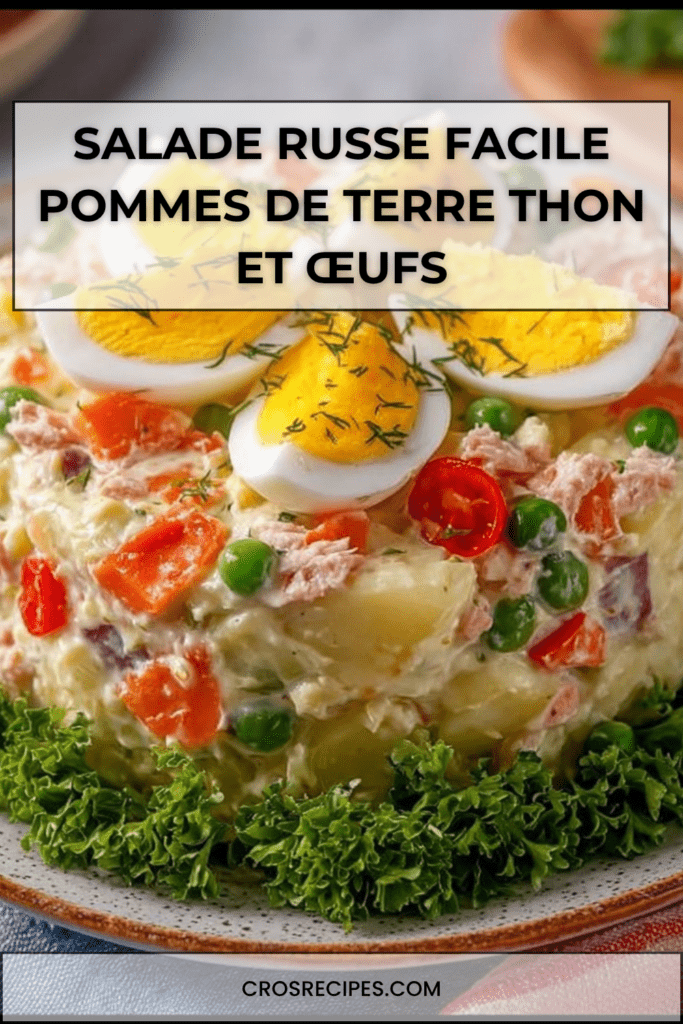 Salade russe crémeuse avec pommes de terre en dés, thon émietté, œufs en quartiers, petits pois et carottes, décorée d’herbes fraîches.