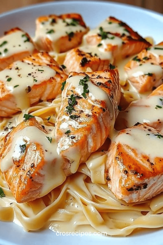 Assiette de pâtes crémeuses au saumon grillé nappées d’une sauce fromagère onctueuse, garnies de persil frais et servies bien chaudes.