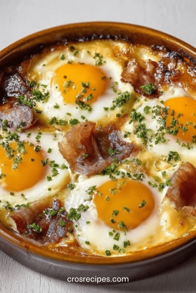 Ramequins d’œufs cocotte crémeux au four avec crème fraîche, lardons, fromage râpé et ciboulette, servis chauds juste après cuisson.