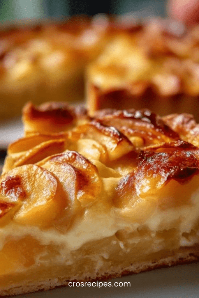 Tarte aux pommes fondantes avec crème vanillée dorée, disposées en fines lamelles sur une pâte sablée croustillante, légèrement caramélisée et brillante.