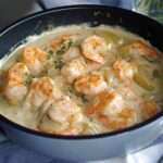 Assiette de blanquette de Saint-Jacques et crevettes dans une sauce crémeuse légère, servie chaude avec herbes fraîches et accompagnement raffiné