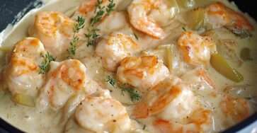 Assiette de blanquette de Saint-Jacques et crevettes dans une sauce crémeuse légère, servie chaude avec herbes fraîches et accompagnement raffiné