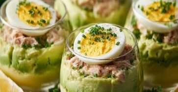 Verrines avocat thon et œufs mimosa dressées en couches, avec avocat crémeux, thon assaisonné et demi-œuf mimosa décoré de ciboulette.
