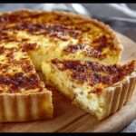 Quiche lorraine traditionnelle dorée, avec pâte croustillante et garniture crémeuse aux œufs et lardons, servie en parts.
