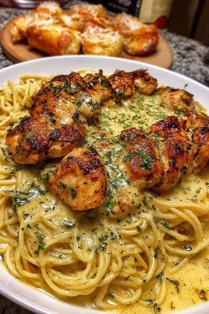Assiette de spaghetti crémeux au poulet doré, nappés d’une sauce onctueuse à l’ail et au parmesan, décorés de persil frais dans un cadre chaleureux.
