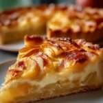 Tarte aux pommes fondantes avec crème vanillée dorée, disposées en fines lamelles sur une pâte sablée croustillante, légèrement caramélisée et brillante.