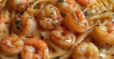 Assiette de spaghetti crémeux aux crevettes avec sauce à l’ail onctueuse, crevettes rosées et persil frais, servie chaude.