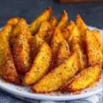 Potatoes wedges dorées et croustillantes au parmesan, avec peau, disposées sur une plaque, texture fondante à l’intérieur.