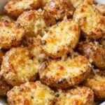 Pommes de terre grenaille rôties au four, dorées et croustillantes, enrobées de parmesan fondu, d’ail et d’herbes, servies chaudes dans un plat rustique.