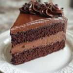 Gâteau au chocolat coupé en deux couches, garni d’une mousse aérienne, recouvert d’une ganache brillante et lisse, avec une texture fondante et intense.