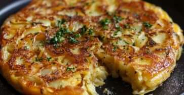 Tortilla espagnole épaisse aux pommes de terre et oignons, dorée à l’extérieur et fondante à l’intérieur, coupée en parts sur une assiette.