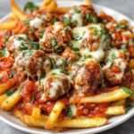 Frites de boulettes panées dorées et croustillantes, garnies de fromage fondant, servies chaudes avec sauce marinara dans un plat rustique.