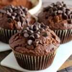 Muffins légers au chocolat disposés sur une grille, à la texture moelleuse, préparés avec de la compote de pommes, décorés de quelques pépites de chocolat.