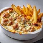 Cassolettes de poulet nappé d’une sauce crémeuse au maroilles, servies avec des frites maison dorées et croustillantes, décorées de persil frais.