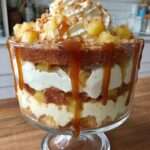 Verrines pommes composées de couches de pommes fondantes, crème légère au fromage frais et caramel coulant, décorées de biscuits émiettés et morceaux de pommes.