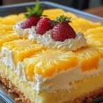 Gâteau ananas garni de chantilly légère, décoré de tranches d’ananas et de fraises fraîches sur le dessus.