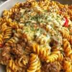 Gratin de fusillis au bœuf et fromage avec pâtes enrobées de sauce tomate crémeuse, viande fondante et fromage gratiné doré.