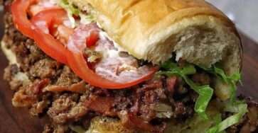 Sandwich Chopped Cheese garni de bœuf haché grillé, fromage fondant, laitue, tomates et sauce dans un pain brioché moelleux.