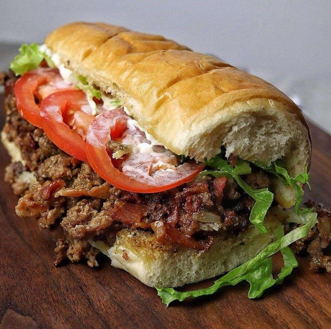 Sandwich Chopped Cheese garni de bœuf haché grillé, fromage fondant, laitue, tomates et sauce dans un pain brioché moelleux.