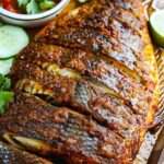 Poisson entier grillé doré et croustillant, mariné aux épices, servi avec citron vert, concombre et sauce pimentée aux herbes.