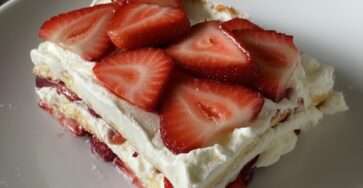 Gâteau fraises et crème façon tiramisu présenté en parts, avec biscuits imbibés, crème mascarpone légère et fraises fraîches en décoration.