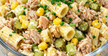 Salade froide de pâtes au thon et maïs servie dans un bol, avec céleri croquant, cornichons, sauce crémeuse au yaourt et ciboulette fraîche.