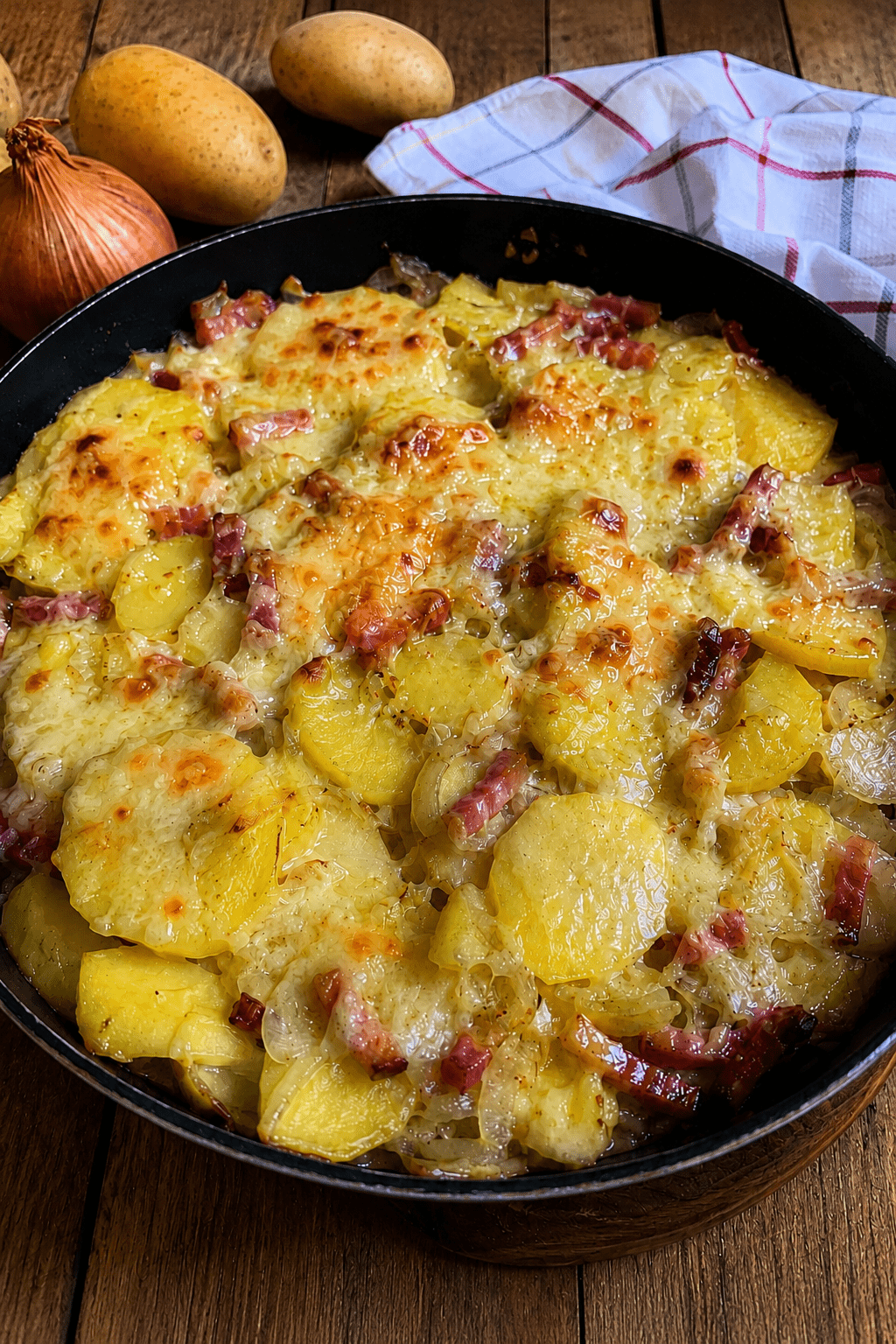 Tartiflette express à la poêle servie bien chaude, avec des pommes de terre dorées, des lardons, des oignons fondants et du reblochon coulant sur le dessus.